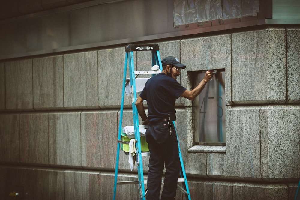 Hausmeister arbeitet auf einer Leiter